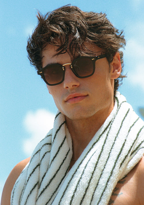 CAMPBELL | Black + Black Tea 18K Handcrafted, luxury black acetate medium round KREWE sunglasses with gold stainless steel metal hardware mens model | Model: Hayden