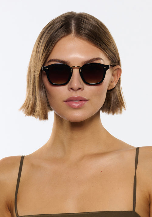 CAMPBELL | Black + Black Tea 18K Handcrafted, luxury black acetate medium round KREWE sunglasses with gold stainless steel metal hardware womens model | Model: Michelle