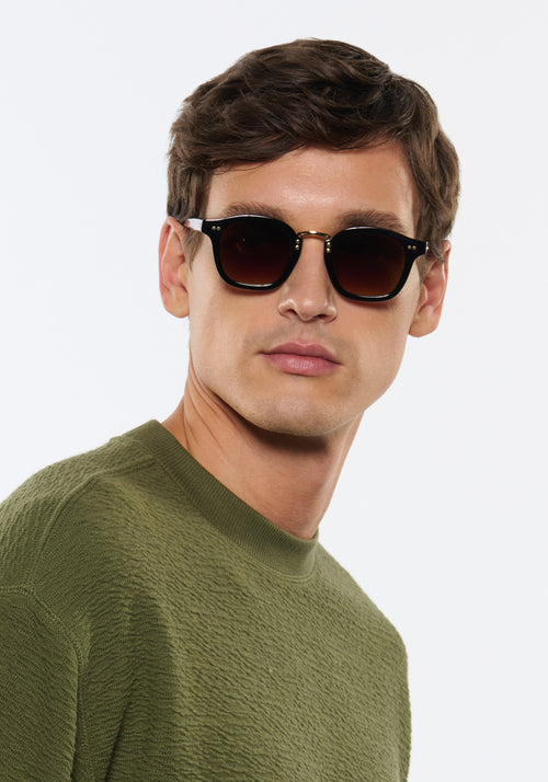 CAMPBELL | Black + Black Tea 18K Handcrafted, luxury black acetate medium round KREWE sunglasses with gold stainless steel metal hardware mens model | Model: Jegor