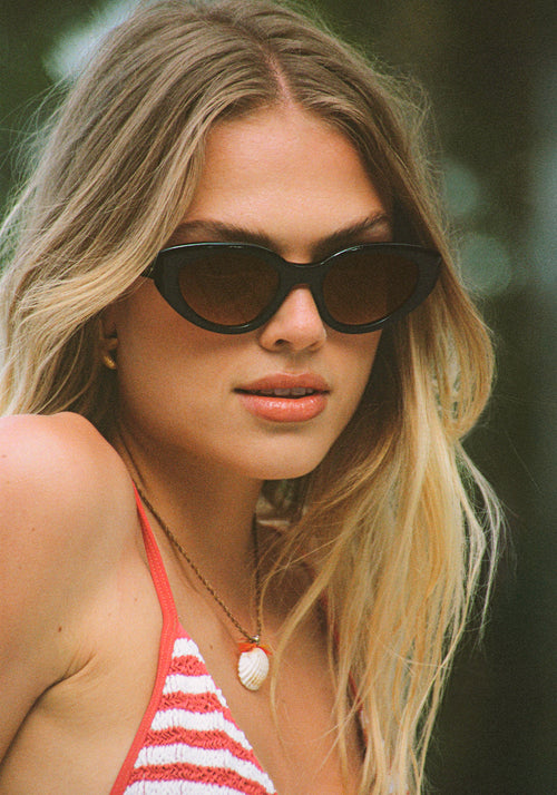 IRENE | Handcrafted, luxury black and black tea acetate medium sized upswept oval wrap KREWE sunglasses womens model | Model: Chané