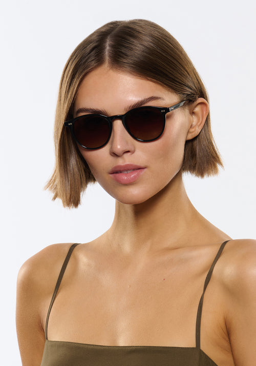 LANDRY | Black + Black Tea Handcrafted, luxury black acetate round KREWE sunglasses womens model | Model: Michelle