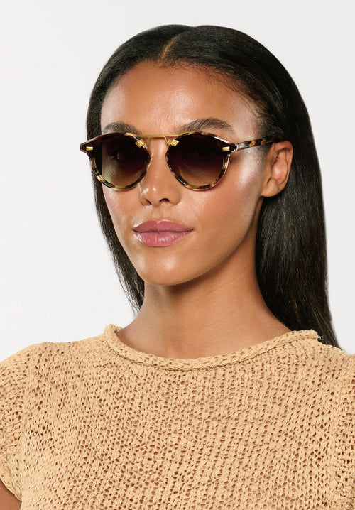 STL NYLON | Blonde Venezia 18K Handcrafted, luxury brown tortoise acetate round KREWE sunglasses with flat edge to edge nylon lens and 18k gold metal bridge womens model | Model: Sasha