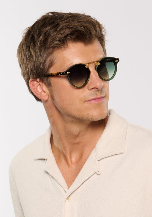 STL NYLON | Bottle Green + Zulu 18K Handcrafted, luxury dark green acetate round KREWE sunglasses with flat edge to edge nylon lens and 18k gold metal bridge mens model | Model: Ben