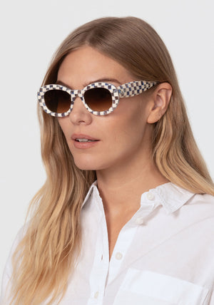 MARGARET | Gingham over Crystal Handcrafted, luxury blue and white checkered gingham acetate medium sized oval bubble frame KREWE sunglasses womens model | Model: Maritza